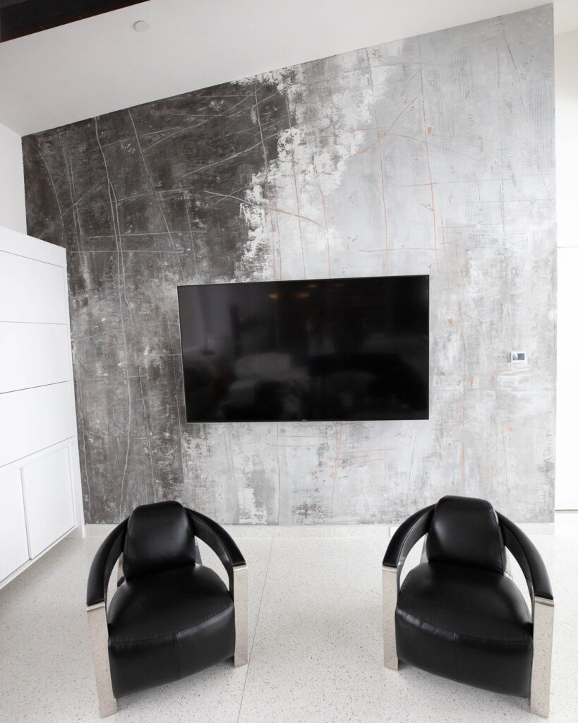 Textural metallic plaster finish in silver, light, and dark greys inspired by sgraffito for a feature wall in mountain modern living room.